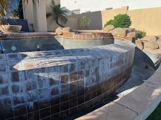 Empty swimming pool with a tile border and surrounding patio.