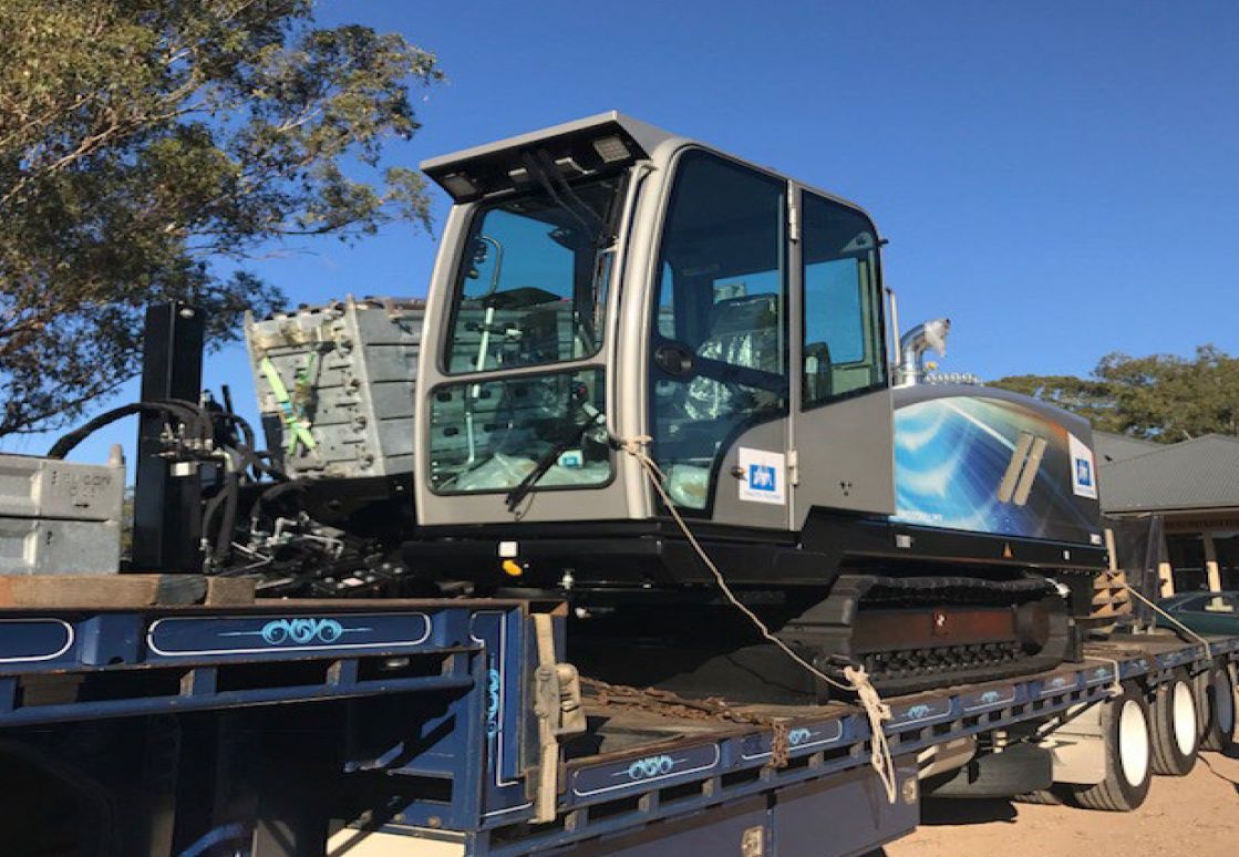 A large excavator is sitting on top of a flatbed truck.