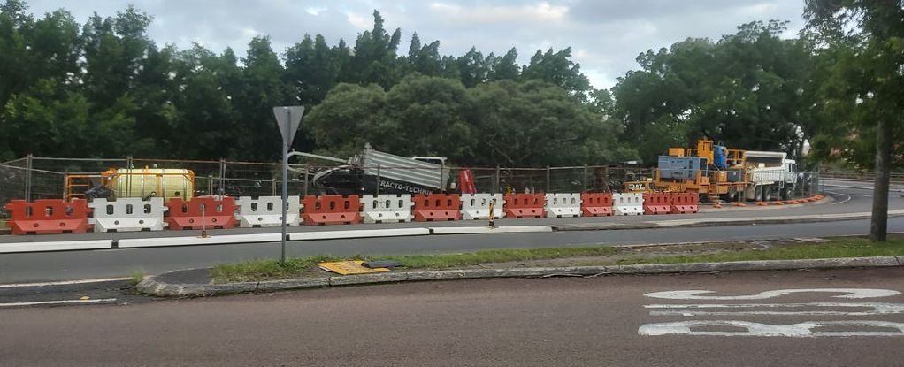 A blurry picture of a road with a fence and trees in the background.
