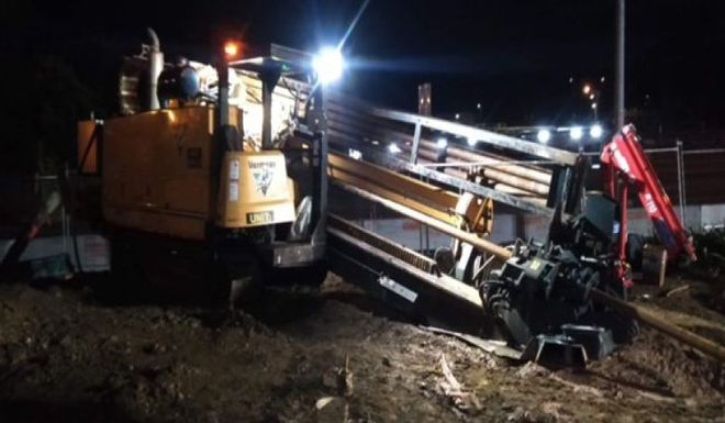 A construction vehicle is sitting in the dirt at night.