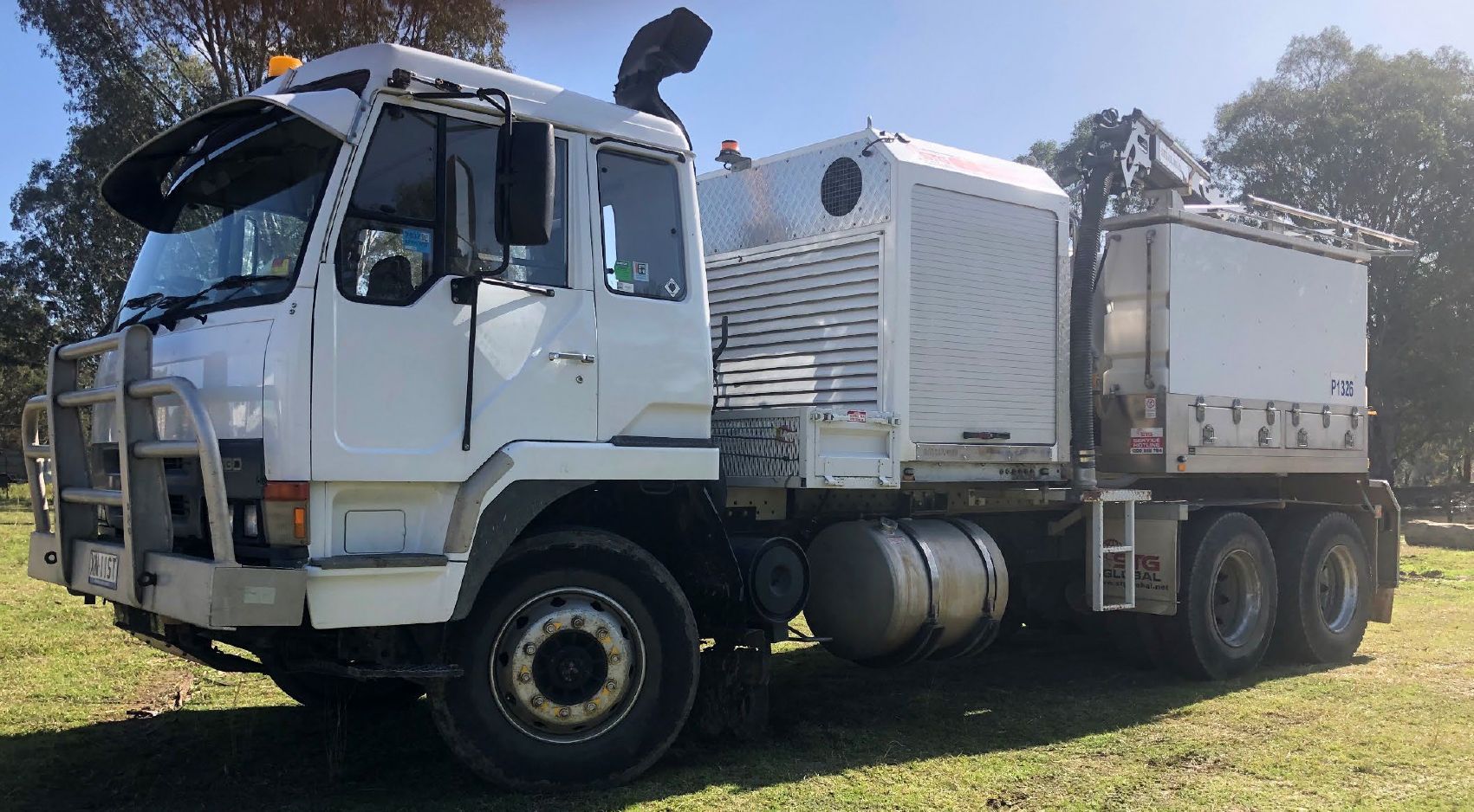 A large white truck is parked in a grassy field.