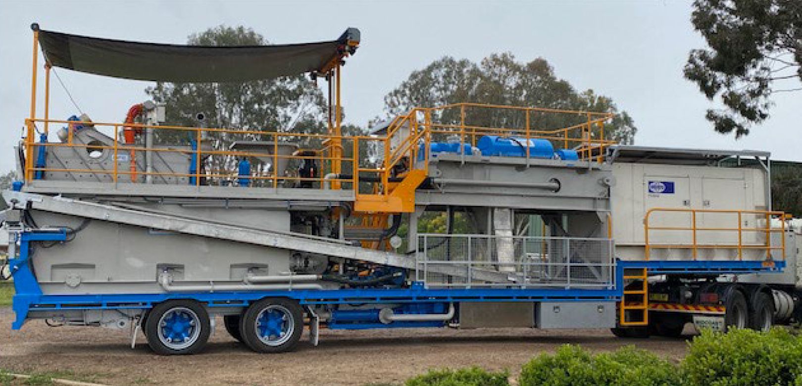 A large blue and white trailer is parked in a field.