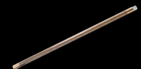 A long brass rod is sitting on a black surface.