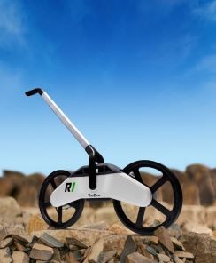 A white bicycle with the word ri on the side is sitting on a pile of rocks.