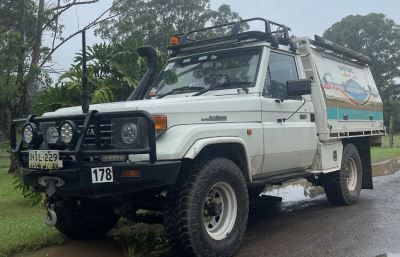 A white truck with a canopy on top of it is parked on the side of the road.