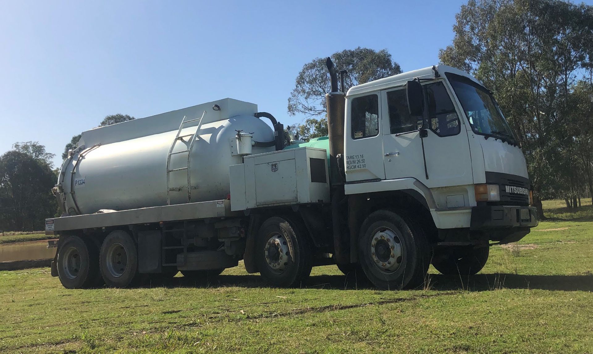 A large white truck is parked in a grassy field.