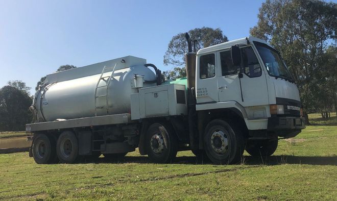 A large white truck is parked in a grassy field.