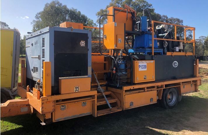 A large orange truck with a trailer attached to it is parked in a field.
