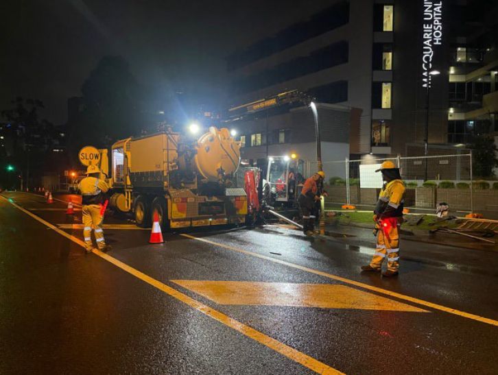 A group of construction workers are working on a street at night.