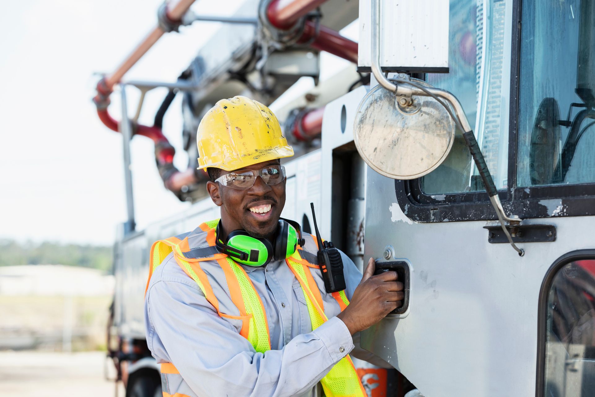 A construction worker wearing a hard hat and safety vest is standing next to a truck.