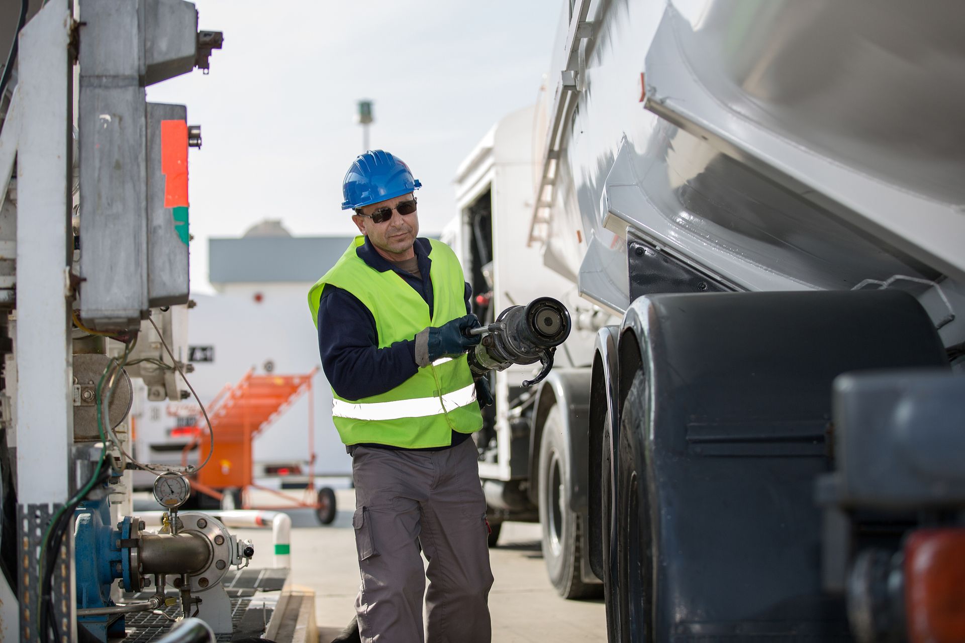 A man is standing next to a truck holding a hose.