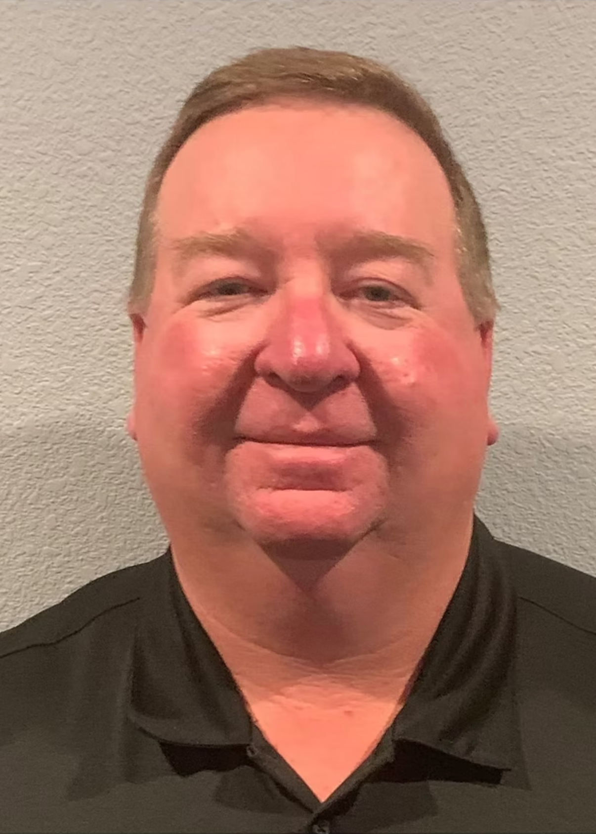 A man in a black shirt is smiling for the camera.