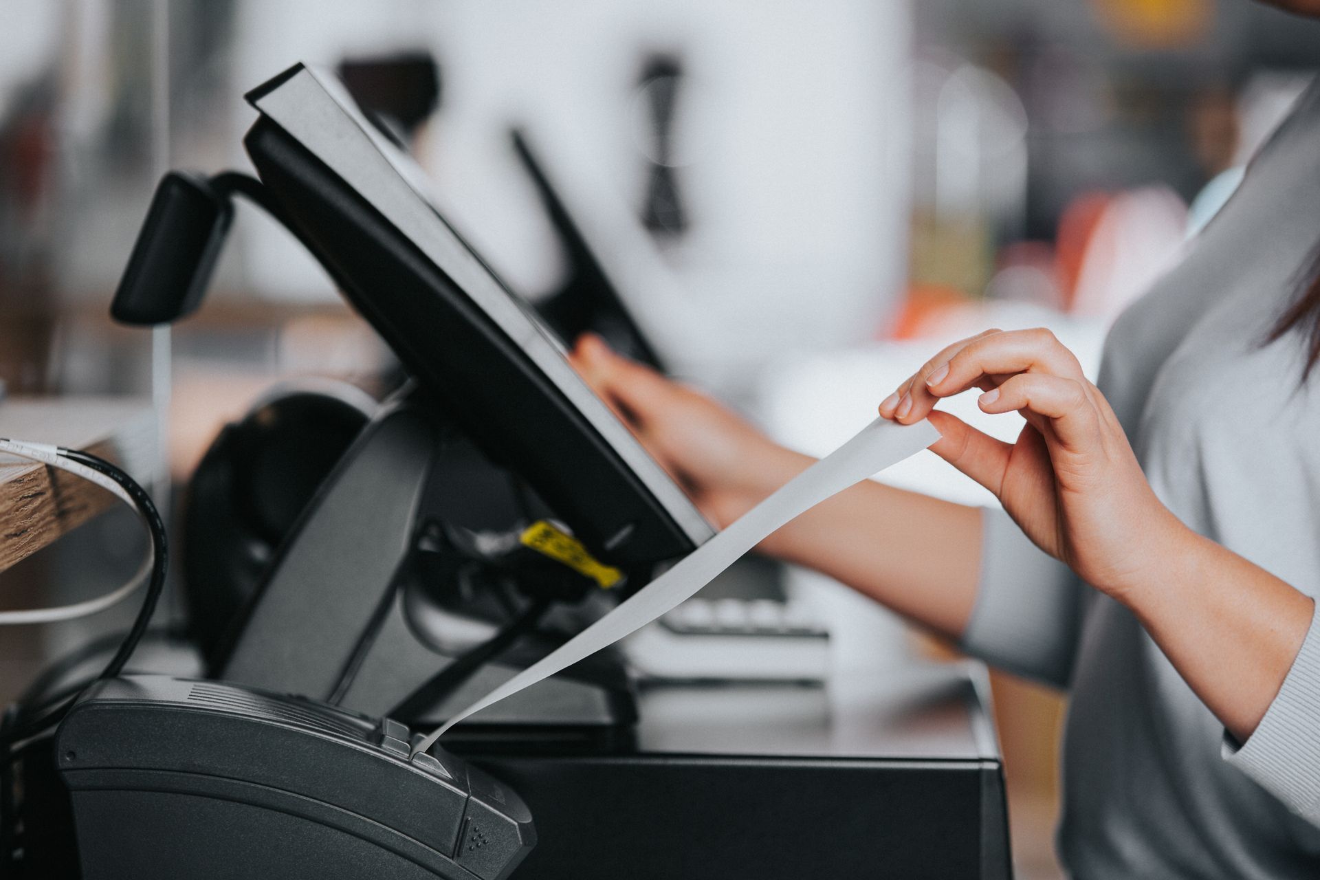 A woman is taking a receipt from a cash register.
