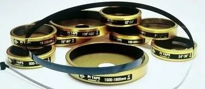 Collection of gold-colored Pi Tapes with black measuring tapes laid across them.