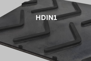 Black rubber conveyor belt surface with raised, L-shaped ridges; label reads 