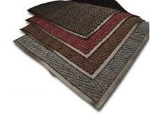 Pile of rectangular area rugs in shades of brown, red, and gray with herringbone patterns and decorative borders.
