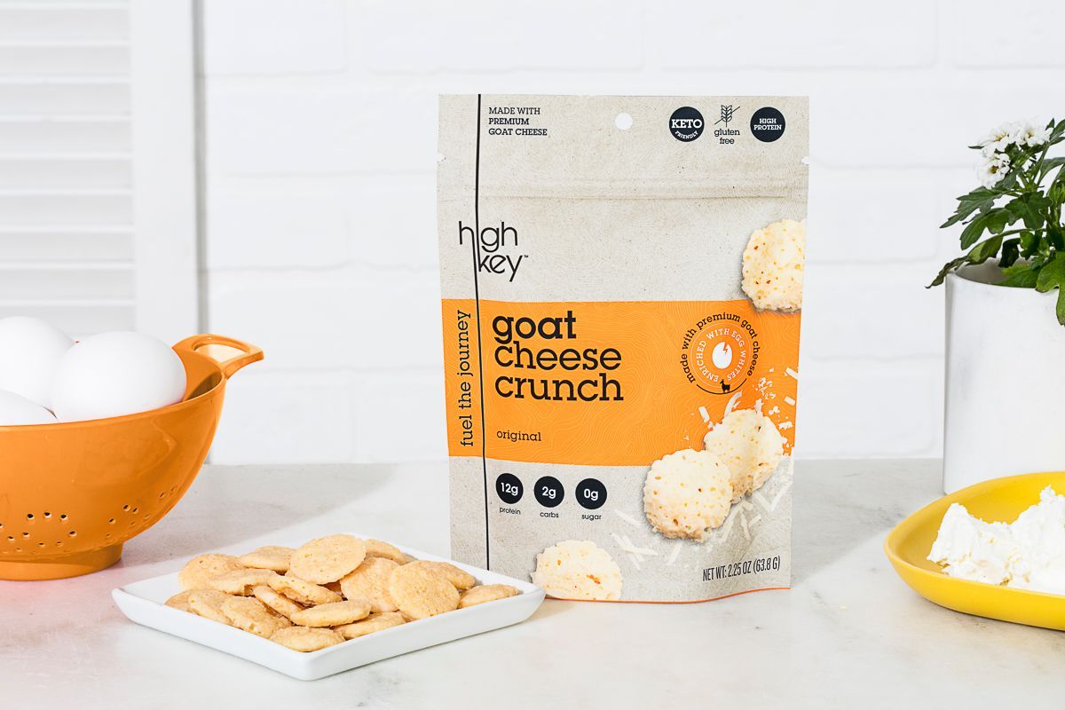 Lifestyle product photography of High Key Goat Cheese Crunch snacks in a kitchen setting with warm orange and yellow details. Product photography by JAM Creative photographers.