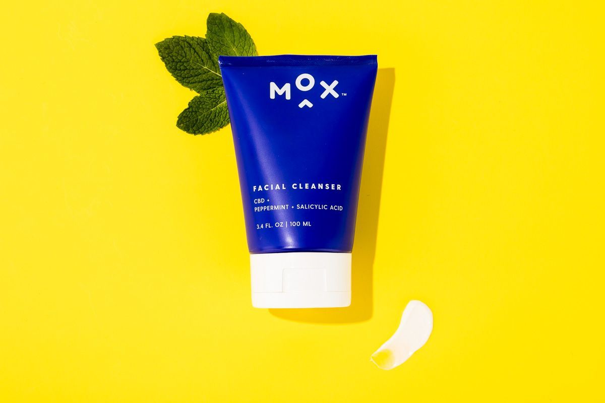 Mox skincare beauty product on yellow paper with fresh mint. By commercial product photographers at JAM Creative.