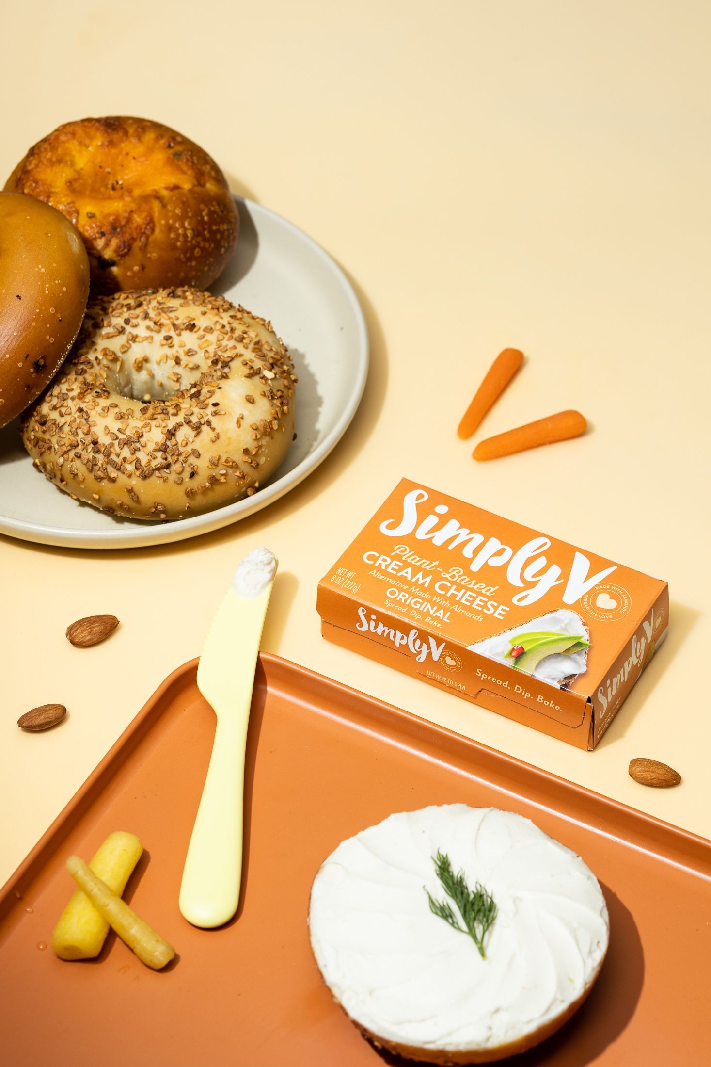 Lifestyle product food photography of Simply cream cheese and bagels on orange. By JAM Creative commercial photography.