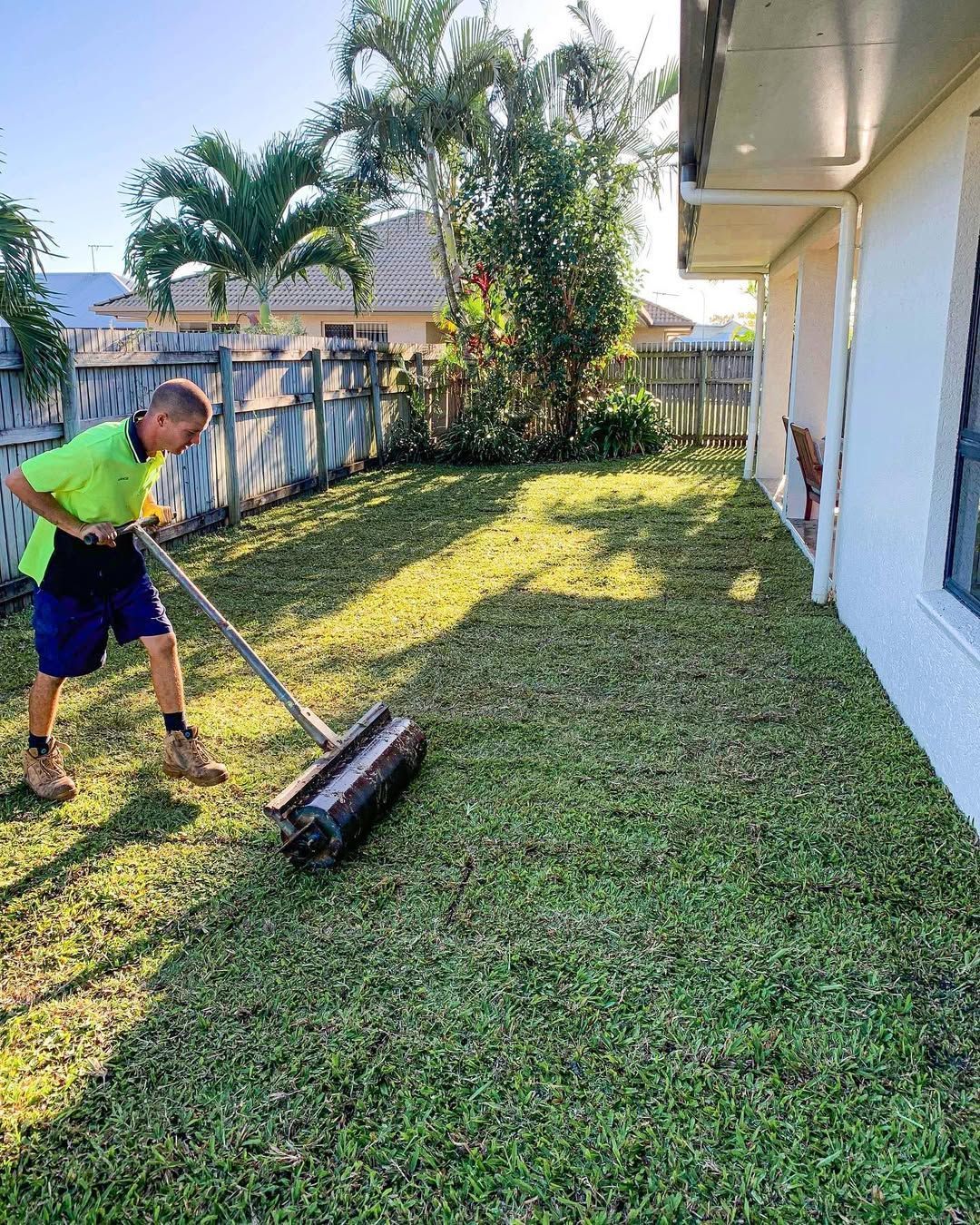 Man Rolling a Lawn in A Yard, Sunny Day — Top Notch Turf in Mackay, QLD