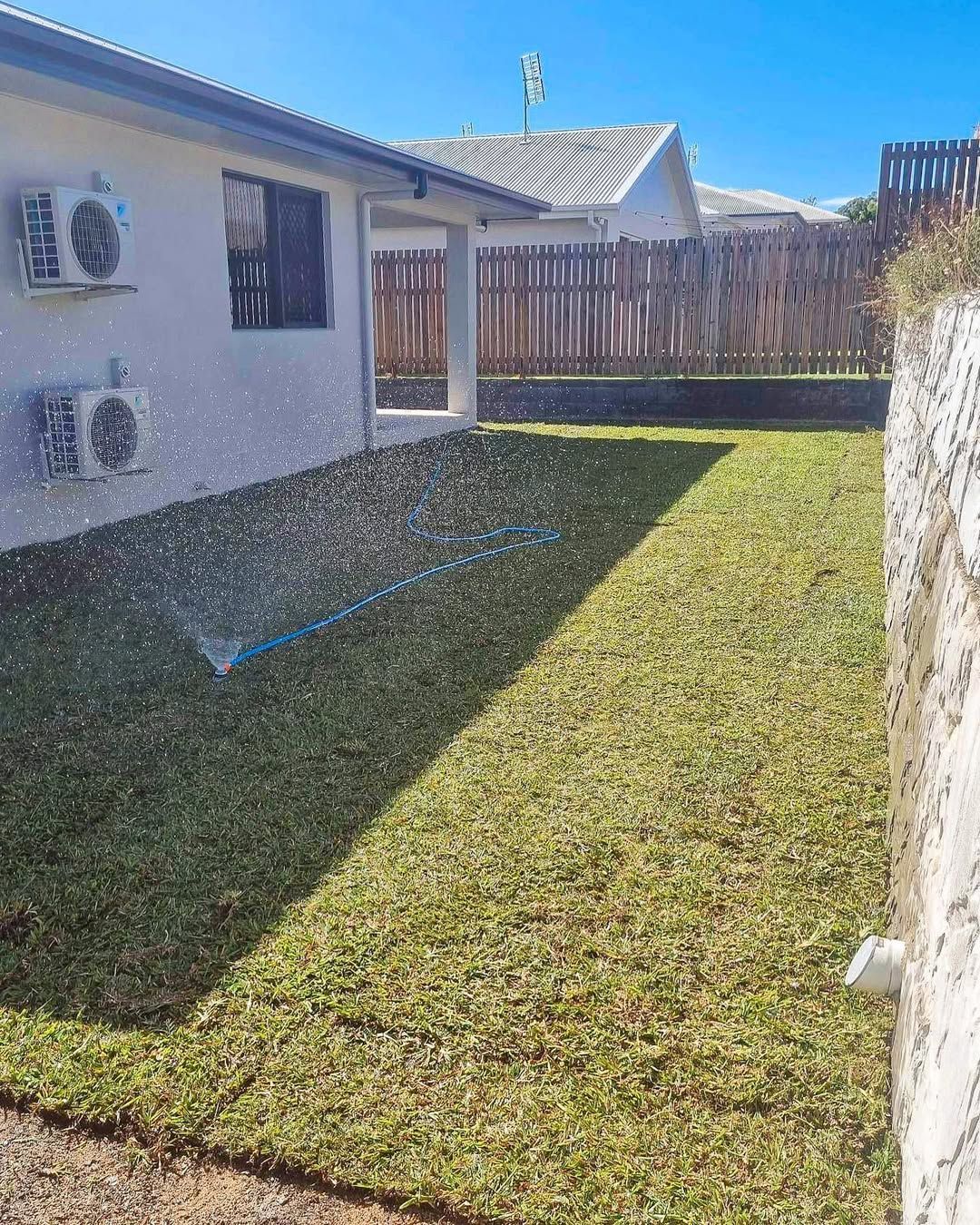 Lawn Being Watered by A Sprinkler in Front of A House — Top Notch Turf in Ayr, QLD