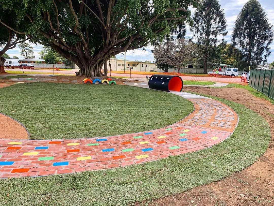 A Curved Brick Pathway Through a Grassy Area in A Playground, Leading to A Tunnel — Top Notch Turf in Ingham, QLD