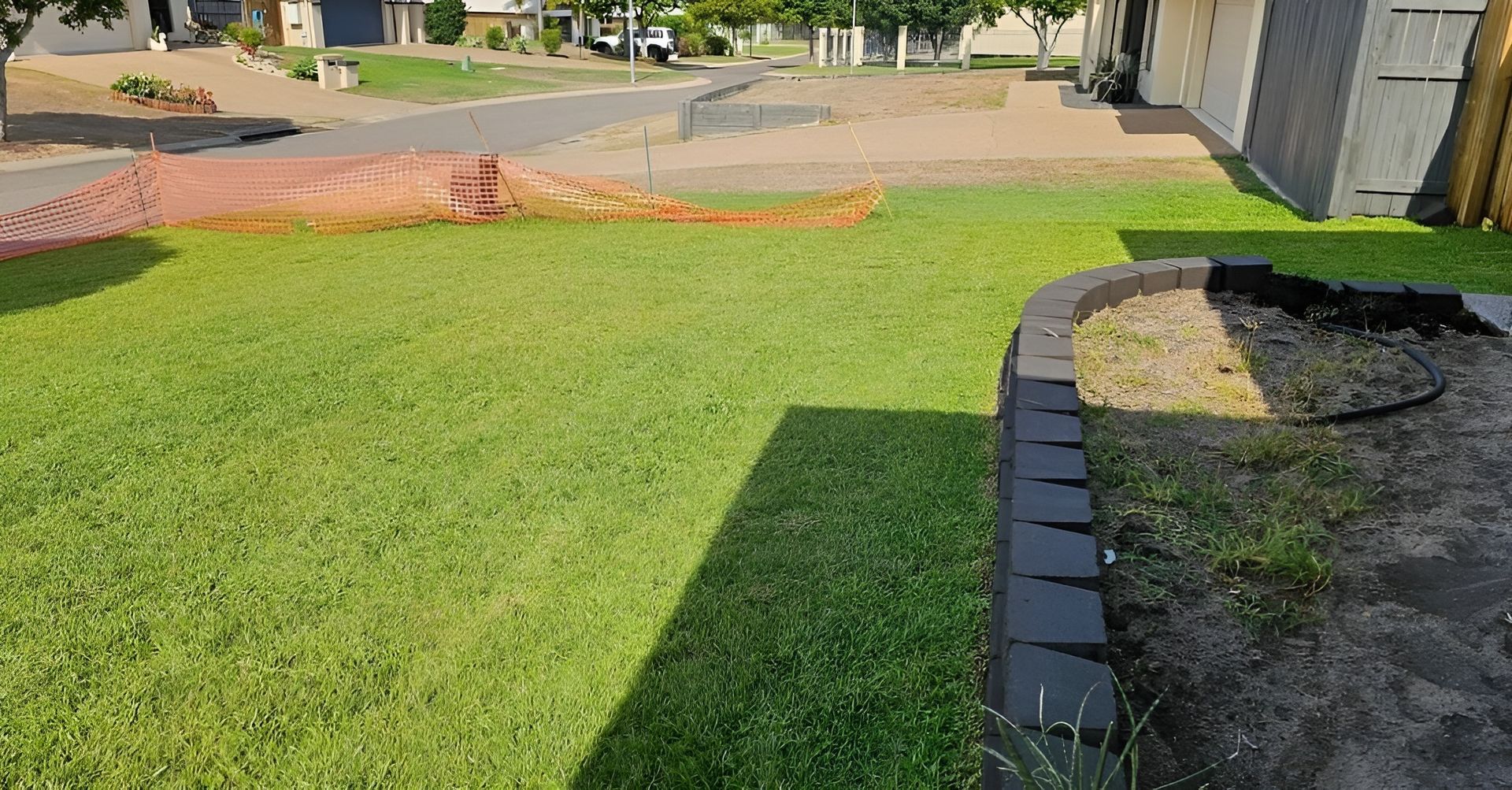 Lush Green Lawn with A Black Brick Border Next to Gravel — Top Notch Turf in Charters Towers, QLD
