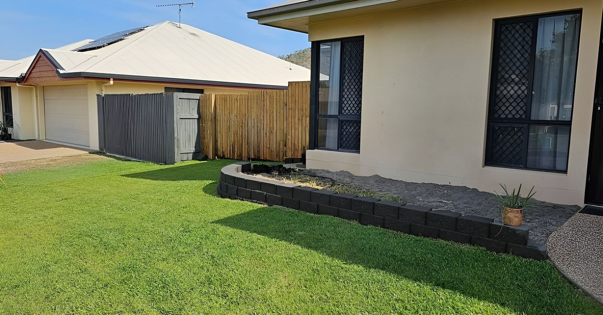 A Beige House with Dark Windows, Adjacent to A Garage and Fence — Top Notch Turf in Mackay, QLD