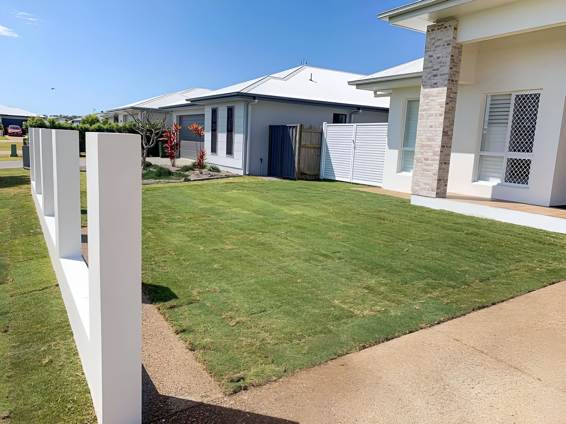 A Green Lawn and A White Fence in Front of A House on A Sunny Day — Top Notch Turf in Charters Towers, QLD