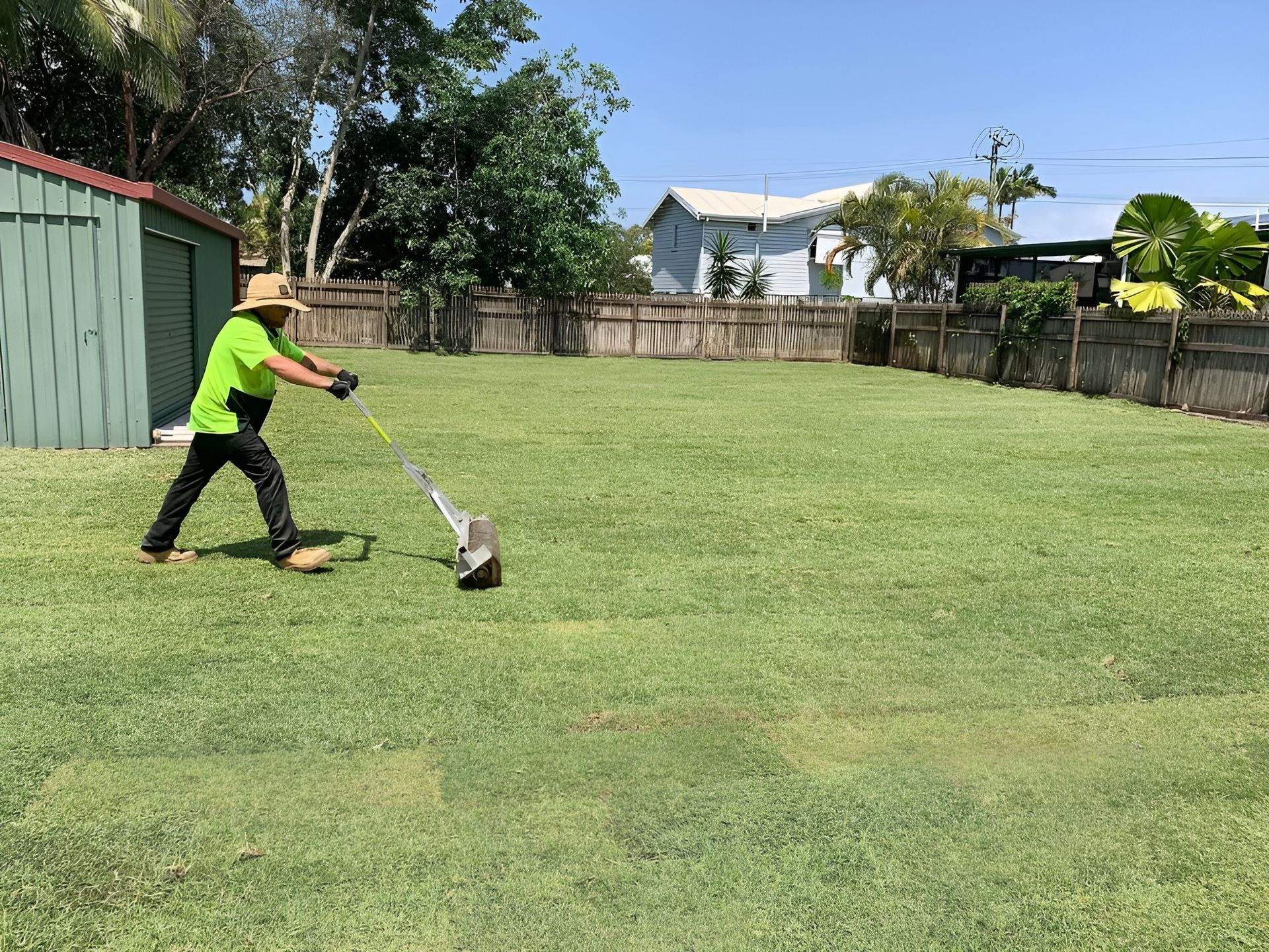 Person Mowing a Large Lawn with A Push Mower, Green Grass, Sunny Day — Top Notch Turf in Cairns, QLD