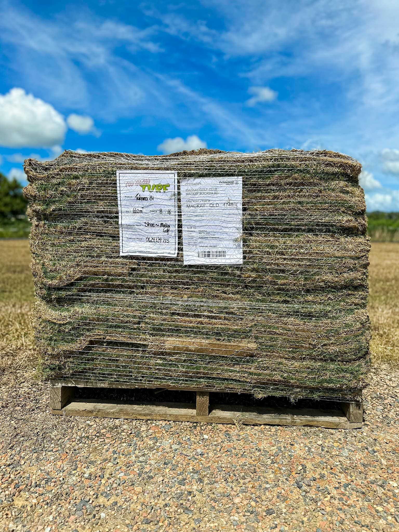 Pallet of Green and Brown Textured Material Under a Blue Sky, with White Labels — Top Notch Turf in Winton, QLD