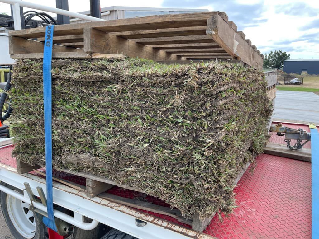 Pallet Loaded with Cut Sod, Secured by Blue Straps, on A Flatbed Truck Outdoors — Top Notch Turf in Cloncurry, QLD