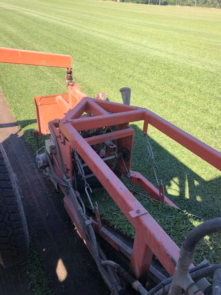 Orange Turf Harvester Cutting Fresh Grass on A Field — Top Notch Turf in Rasmussen, QLD