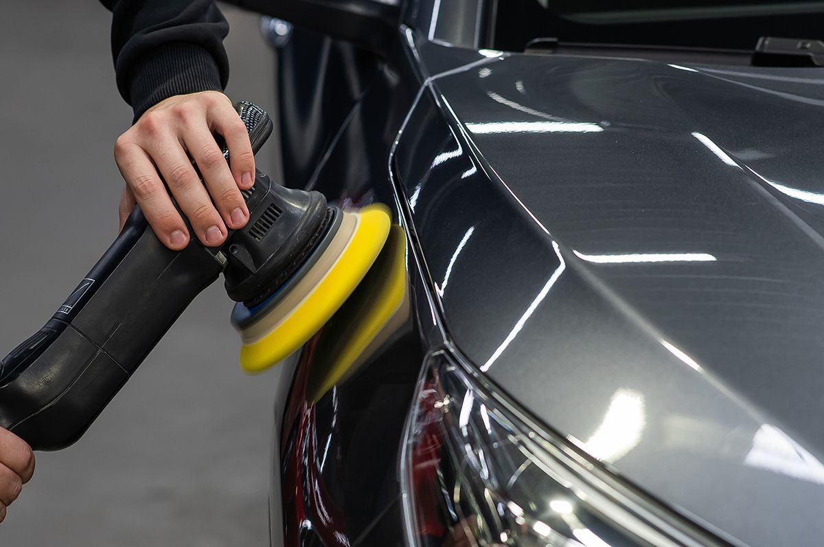 A person is polishing a car with a machine.