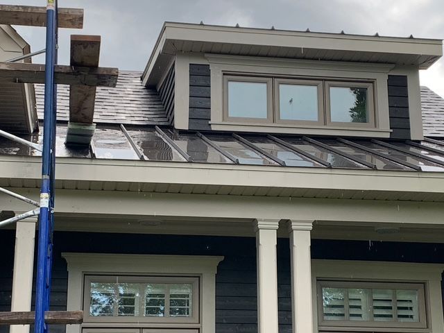 Une personne portant un tablier bleu et des gants blancs utilise un long outil pour nettoyer l'intérieur d'un grand four industriel.