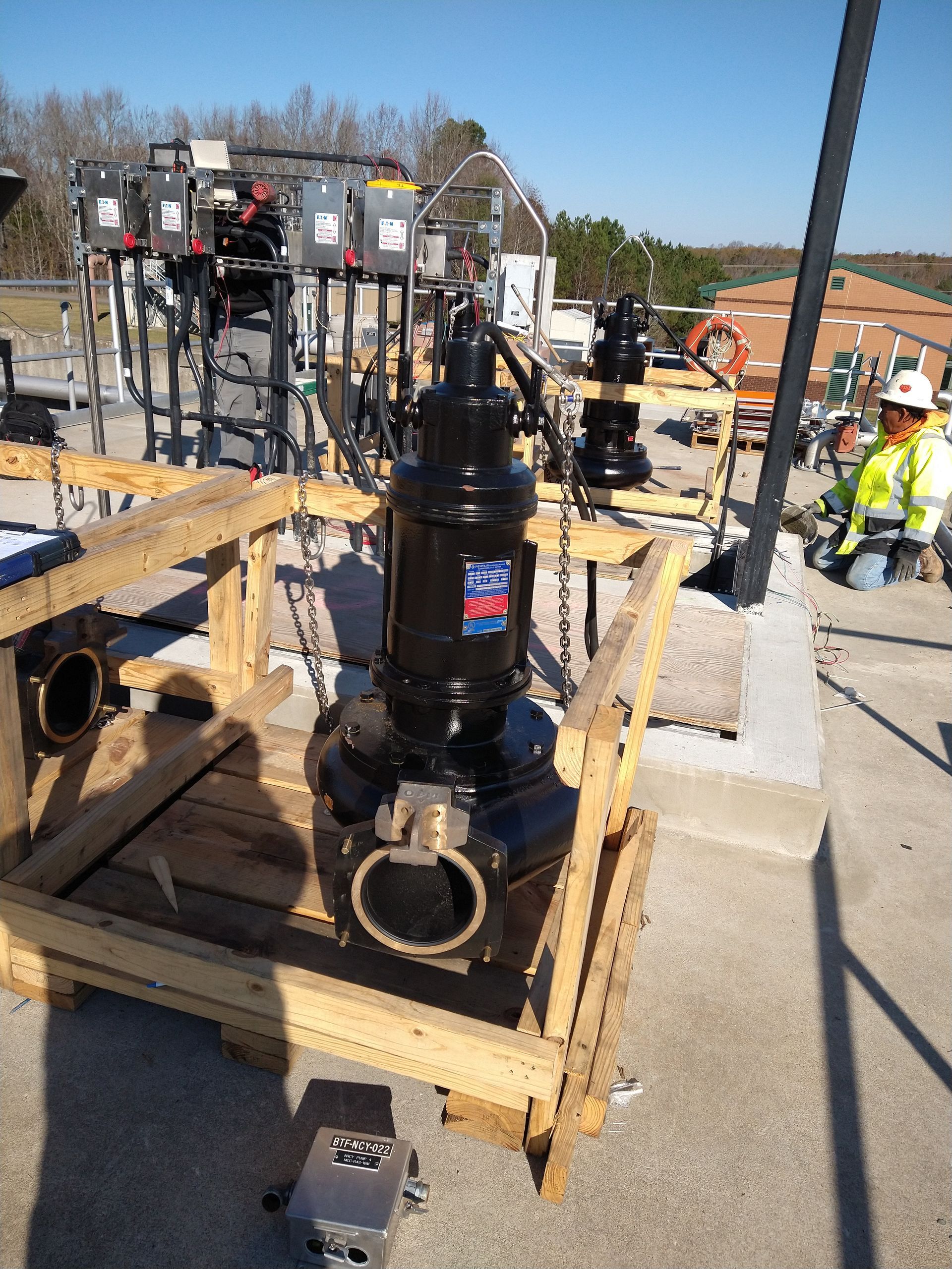 A large black pump is sitting on top of a wooden crate.