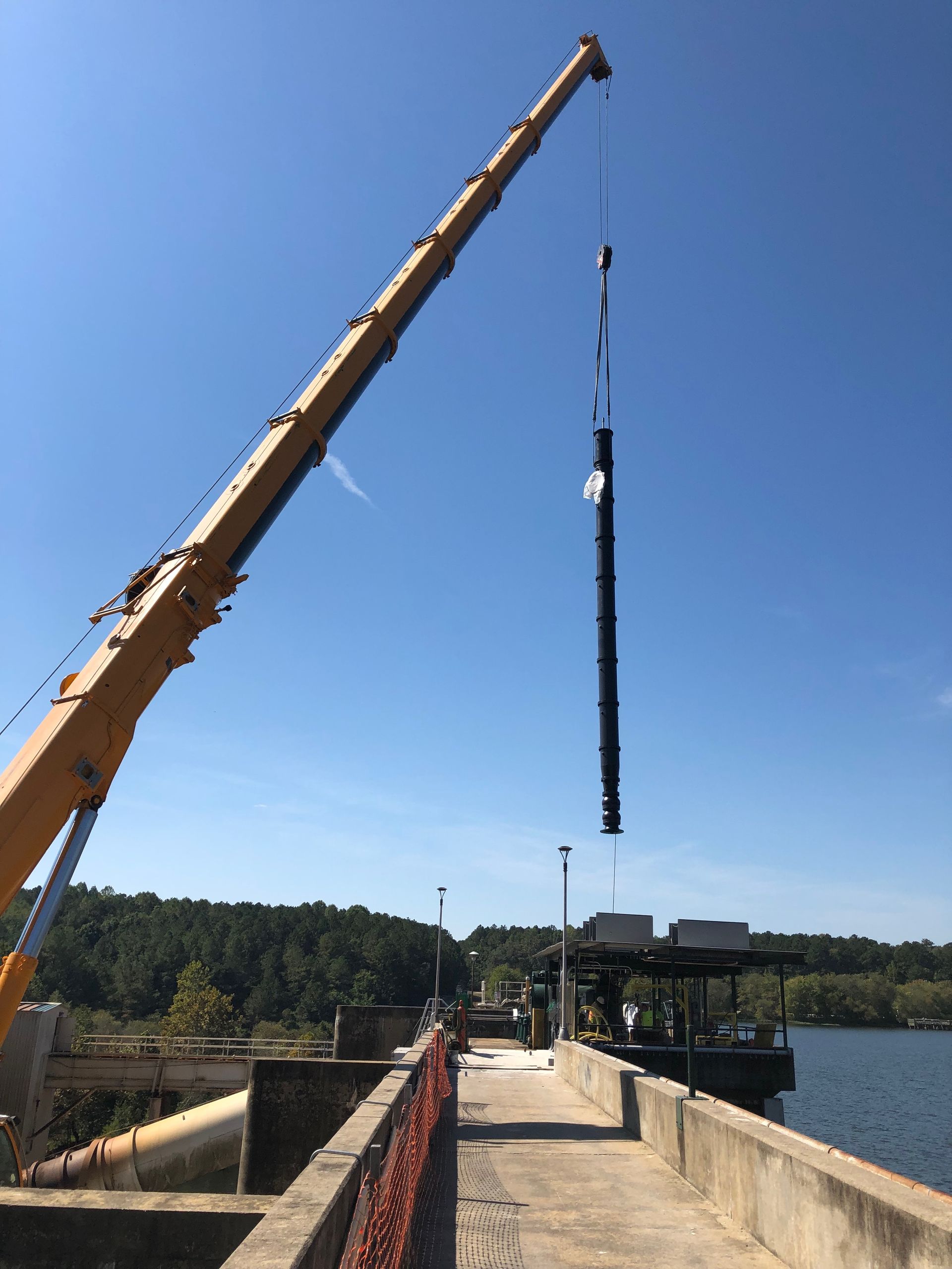 A crane is lifting a large object over a body of water