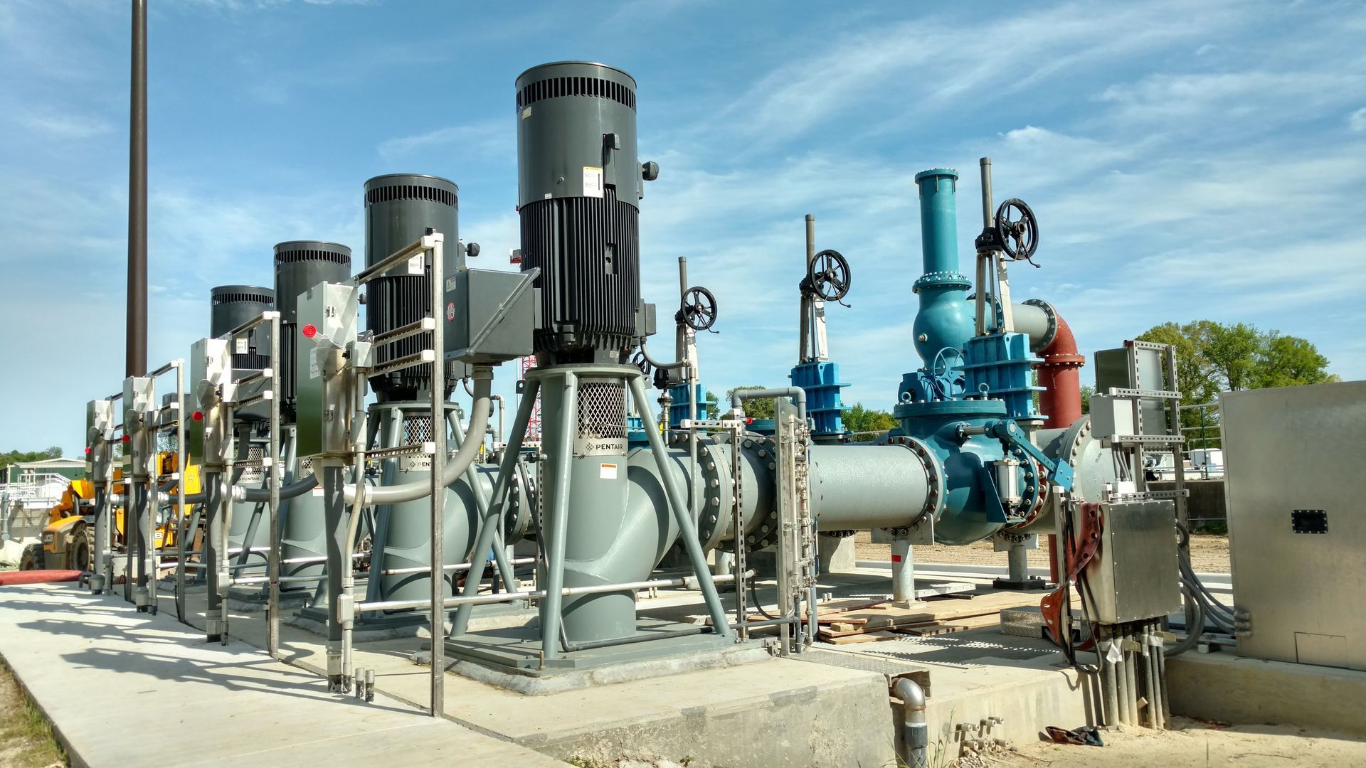 A bunch of pipes and pumps are lined up in a field
