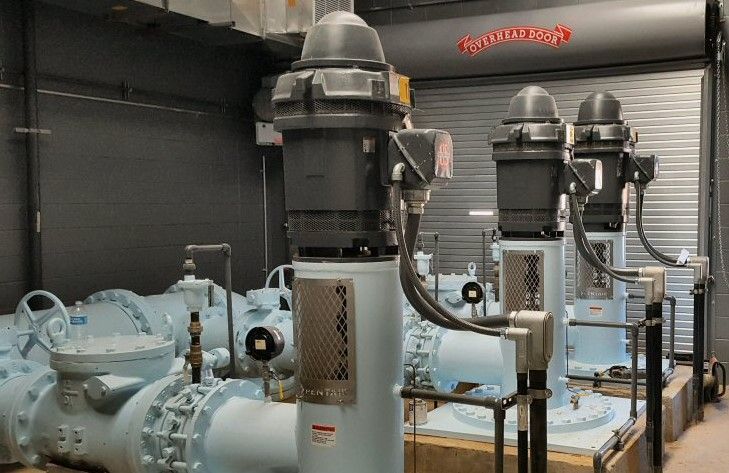 A row of water pumps in a warehouse with a garage door in the background.