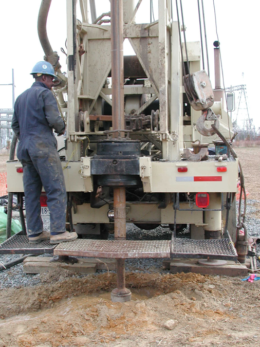 A man wearing a hard hat is working on a machine