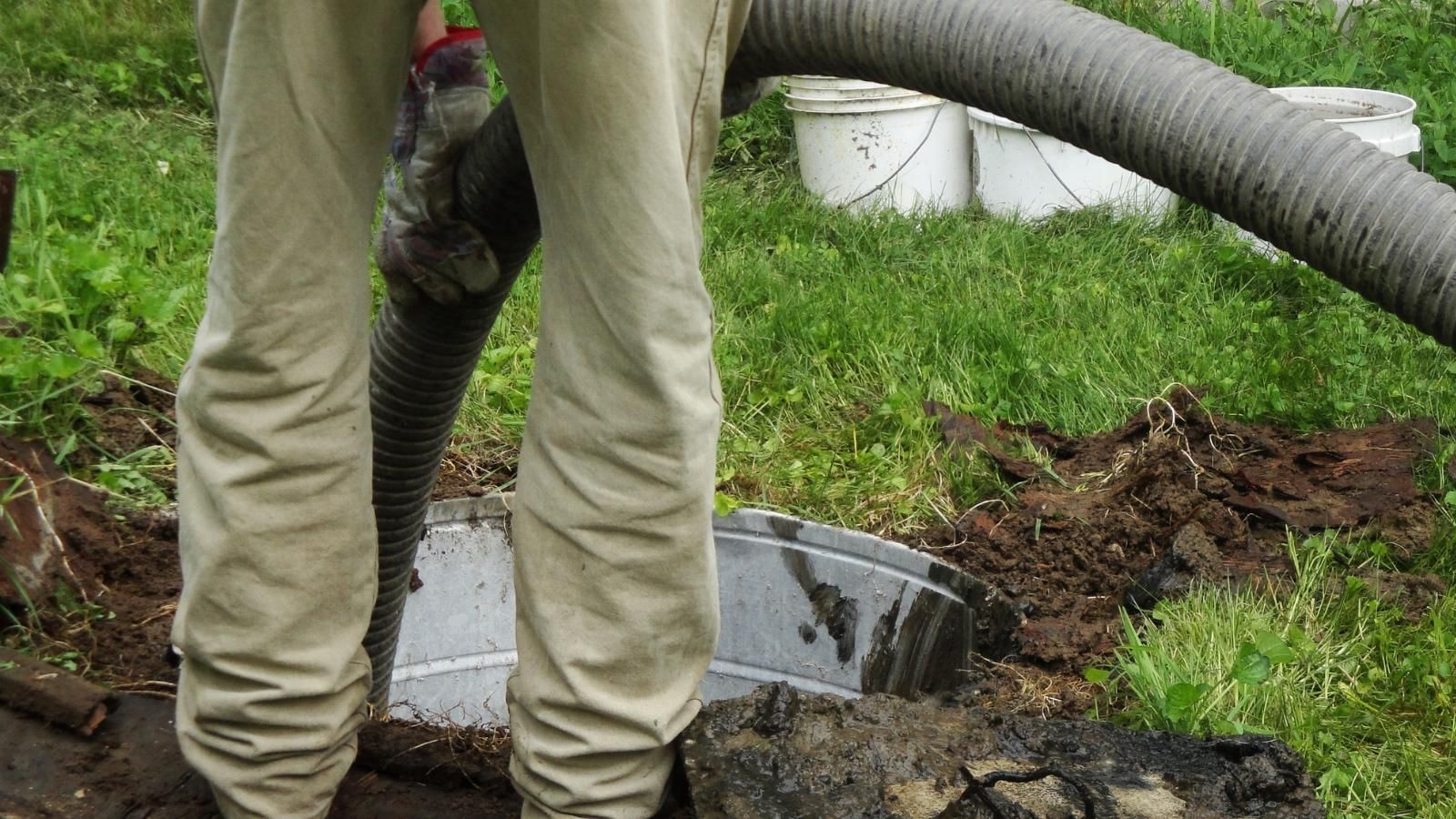 Worker setting up pumping line for septic tank.