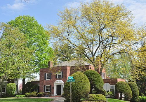 A large brick house with a green street sign in front of it