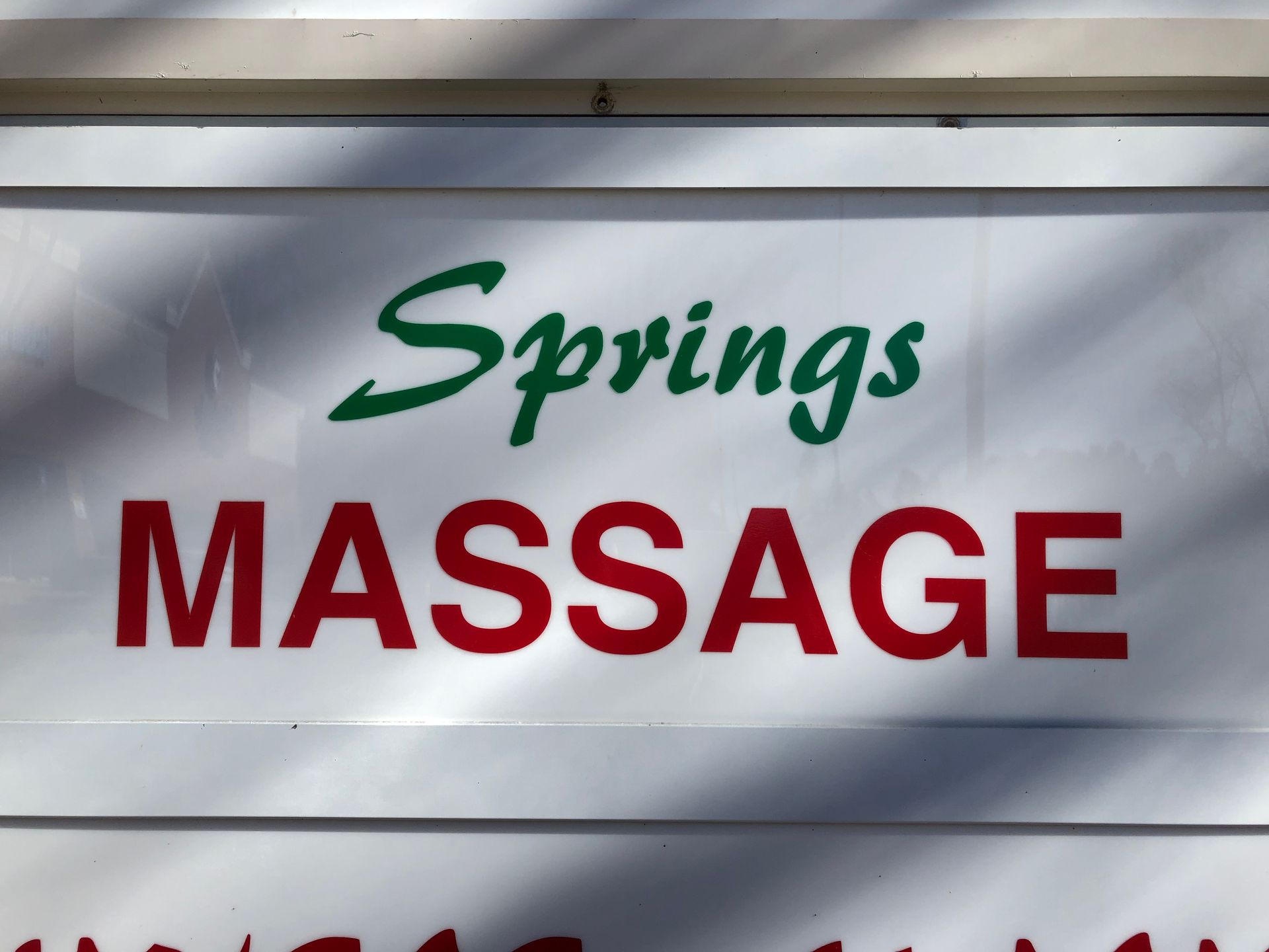 A white sign of Springs Massage, Powder Springs, GA with its colored logo on it.