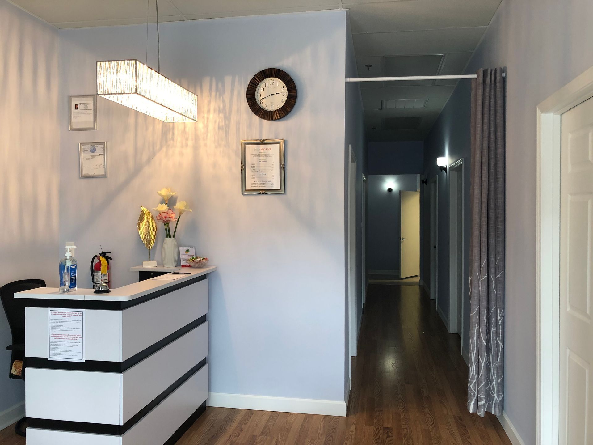 The front desk with decorative lighting, and a hallway leading to treatment rooms in Springs Massage, Powder Springs, GA.