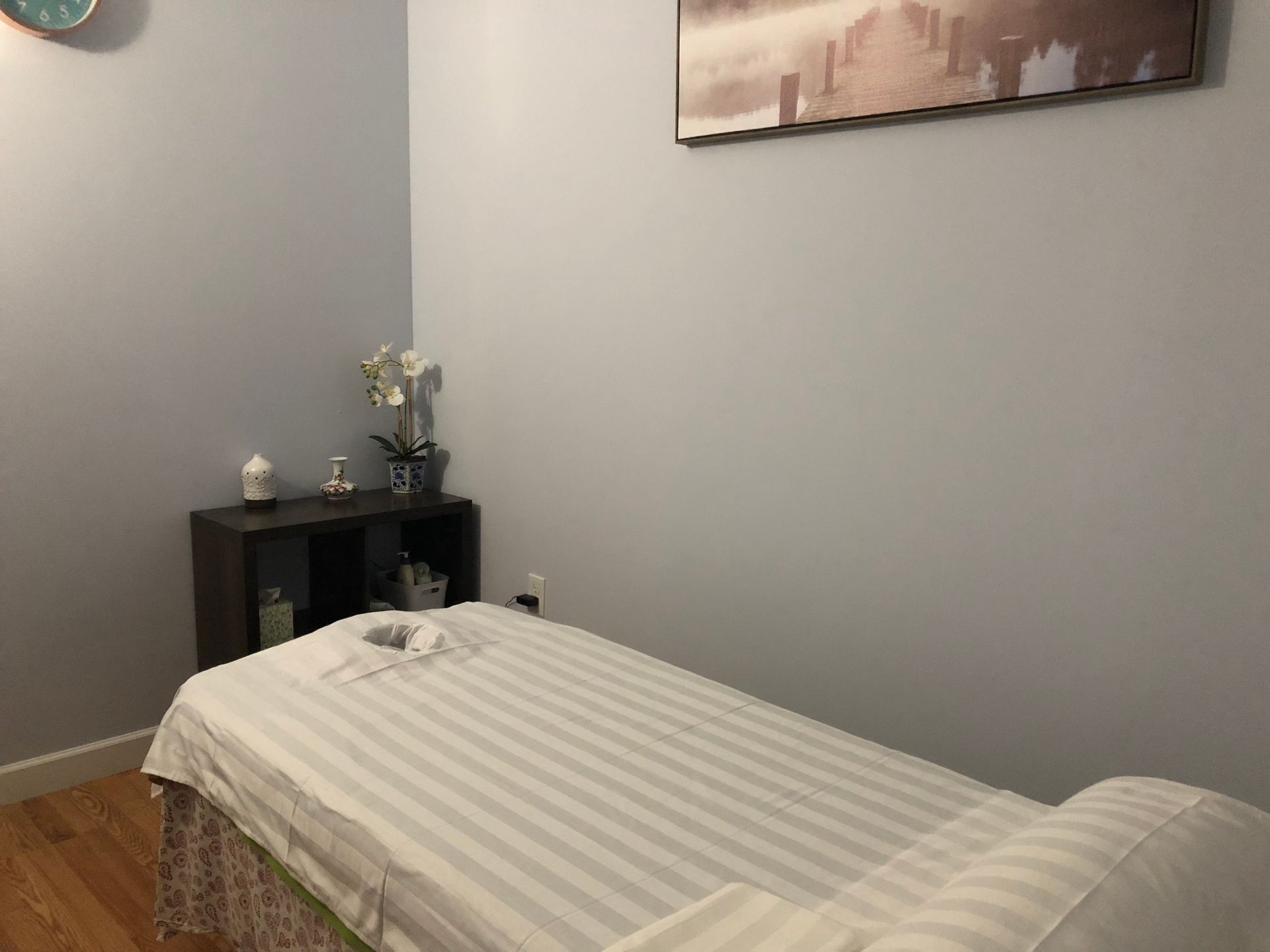 The Springs Massage, Powder Springs massage room with a white massage bed, a small black shelf with decorative items.
