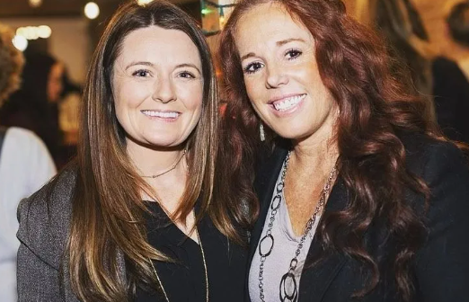 Two women are posing for a picture together and smiling for the camera.