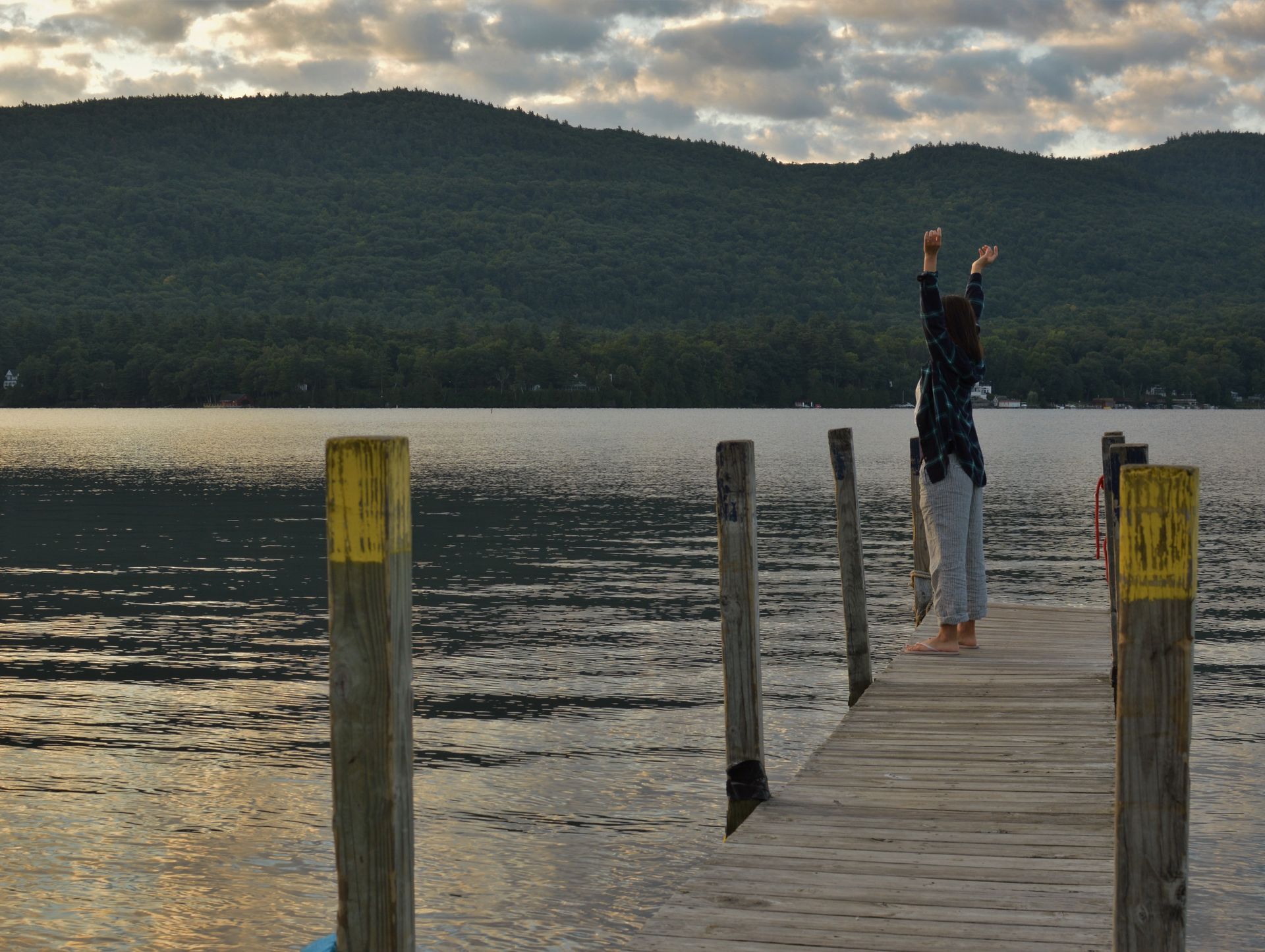 A person standing on a dock with their arms in the air