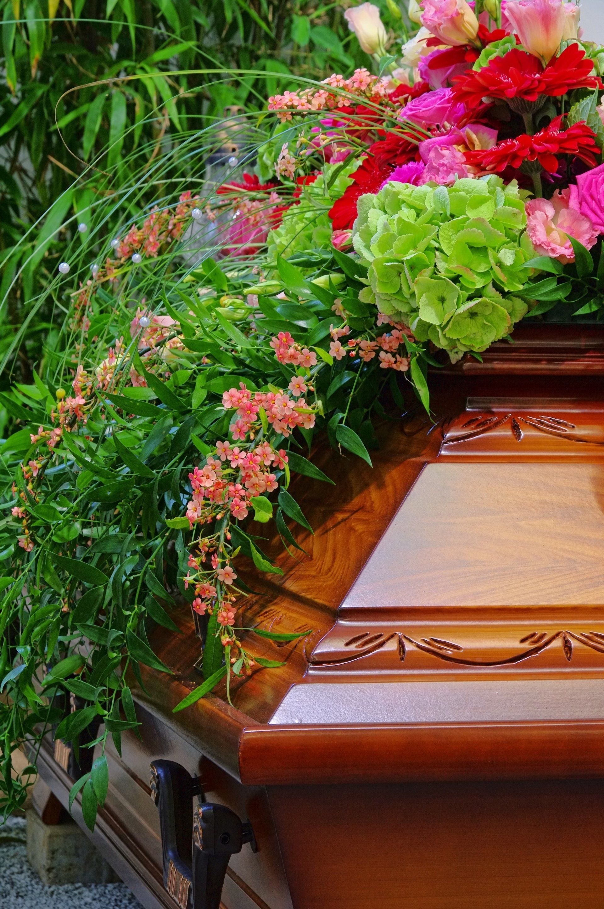 Bara di legno adornata con ghirlanda floreale funebre rosa e verde.