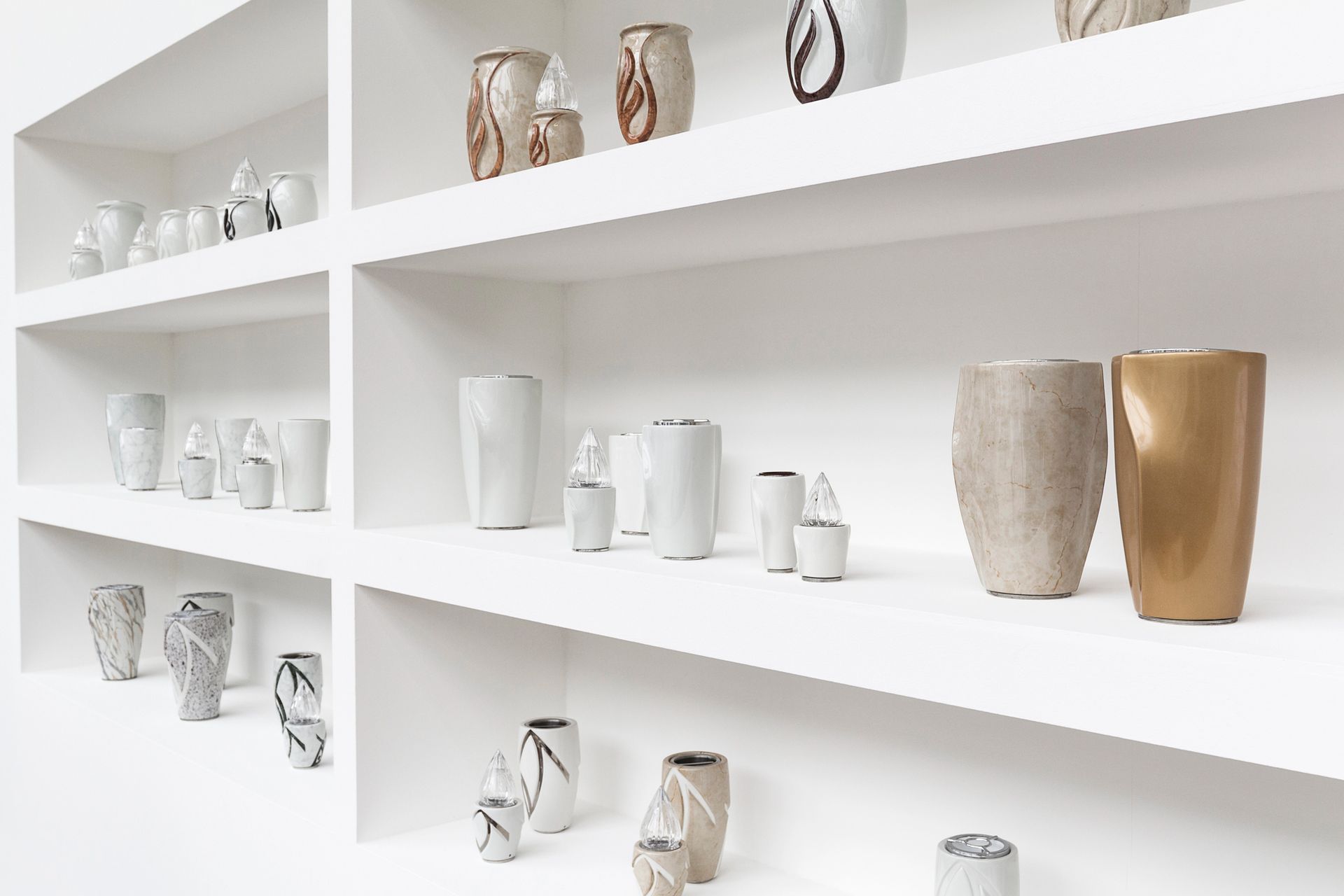 Mensole bianche minimaliste che espongono un assortimento di vasi in ceramica dai toni neutri.