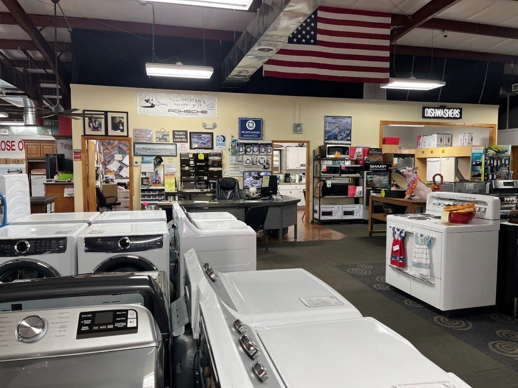 A store filled with lots of appliances and an american flag hanging from the ceiling.